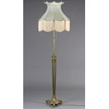 An Edwardian oxidised brass standard lamp in the Adam style, with adjustable column, on three