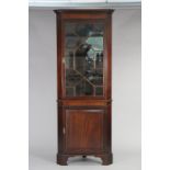 A Georgian mahogany corner cabinet with dentil cornice above three fixed shelves enclosed by an