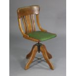 An early 20th century oak swivel office chair, the hard seat upholstered brass-studded green leathe