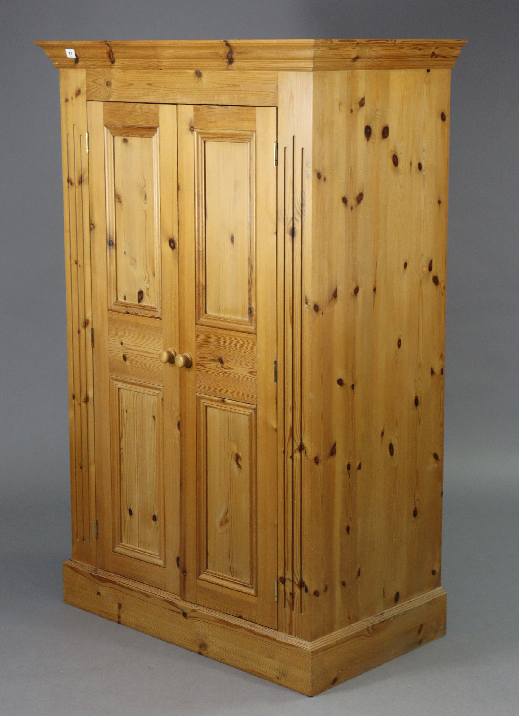 A pine nursery wardrobe enclosed by a pair of fielded panel doors, & on a plinth base, 38” wide x