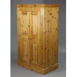 A pine nursery wardrobe enclosed by a pair of fielded panel doors, & on a plinth base, 38” wide x
