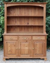 A pine dresser, the upper part fitted two open shelves & with a panelled back, the base fitted three