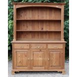 A pine dresser, the upper part fitted two open shelves & with a panelled back, the base fitted three