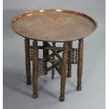 An eastern copper engraved circular tray-top occasional table on a folding wooden stand, 24½”