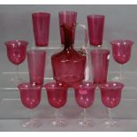 A cranberry glass ewer with clear handle, six ditto wine glasses, & five ditto beakers.
