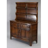 An Ercol oak sideboard/dresser fitted two shelves to the panelled back, the base fitted two frieze