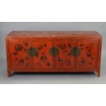 A Chinese red & black lacquered dwarf cabinet with all-over repeating butterfly & floral design,