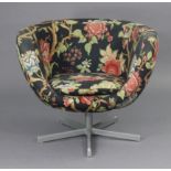A 1960’s swivel tub-shaped chair upholstered multi-coloured floral material, & on silvered-metal