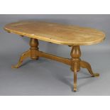 A pine twin-pedestal dining table with rounded ends to the rectangular top, & on vase-turned end