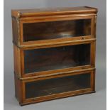 A Globe Wernicke oak three-tier sectional bookcase, each tier enclosed by a glazed lift-up door, 34”