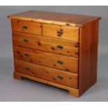 A pine-finish chest fitted two short & three long drawers with brass swing handles, & on a shaped