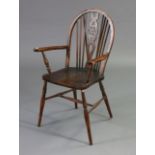 A Windsor-style wheel-back elbow chair with a hard seat, & on turned legs with spindle stretchers.
