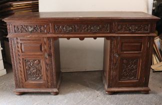 A late 19th/early 20th century carved oak pedestal sideboard fitted three frieze drawers, & each