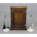 A small oak cupboard enclosed by a panel door, 17” wide x 23” high; & a pair of table lamps.