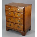 A walnut-finish upright cabinet enclosed by a hinged lift-lid, with fall-front mock-drawers, & on br