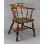 A spindle-back captain’s chair with a hard seat, & on turned legs with spindle stretchers.