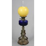 A late 19th/early 20th century cast-brass oil table lamp with a blue glass reservoir, & on a