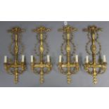 A set of four antique-style gilt-finish wooden twin-branch wall sconces, 10¾” wide x 28½” high, with