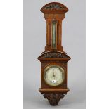 A late 19th century aneroid wall barometer with a 7” diameter white enamel dial, & in a carved