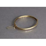 A yellow metal oval stiff hinged bangle of rope-twist design (7.3g).