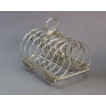 A George IV silver toast rack with six scrolled divisions & centre ring handle, the gadrooned base