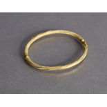 An 18ct yellow gold bangle with sprung hinge & textured rope-twist design (7.5g).