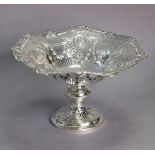 An Edwardian silver circular comport with cast & pierced rim decorated with baskets of flowers &
