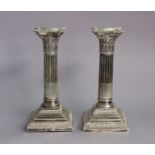 A pair of George V silver candlesticks, the stop-fluted composite columns on square stepped bases