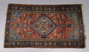 An antique Hamadan rug of madder ground with central lozenge design on a blue field, in multiple