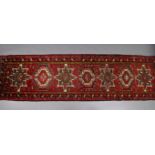 A North West Persian Heriz runner of madder ground with a row of repeating geometric designs