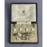 A set of four white metal & mother-of-pearl shirt studs marked “9ct”; a pair of matching cuff-links;