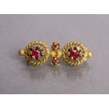 A yellow metal bar brooch with two circular rope-twist panels, each set ruby within a border of tiny