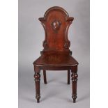 A Victorian mahogany hall chair with carved & shaped back, hard seat & tapering hexagonal legs, 17½”