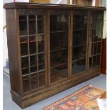 A 1930s German oak bookcase, enclosed by four glazed panel doors with carved foliate decoration,