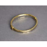 An 18ct yellow gold stiff hinged bangle with sprung hinge & rope-twist design (6.9g).
