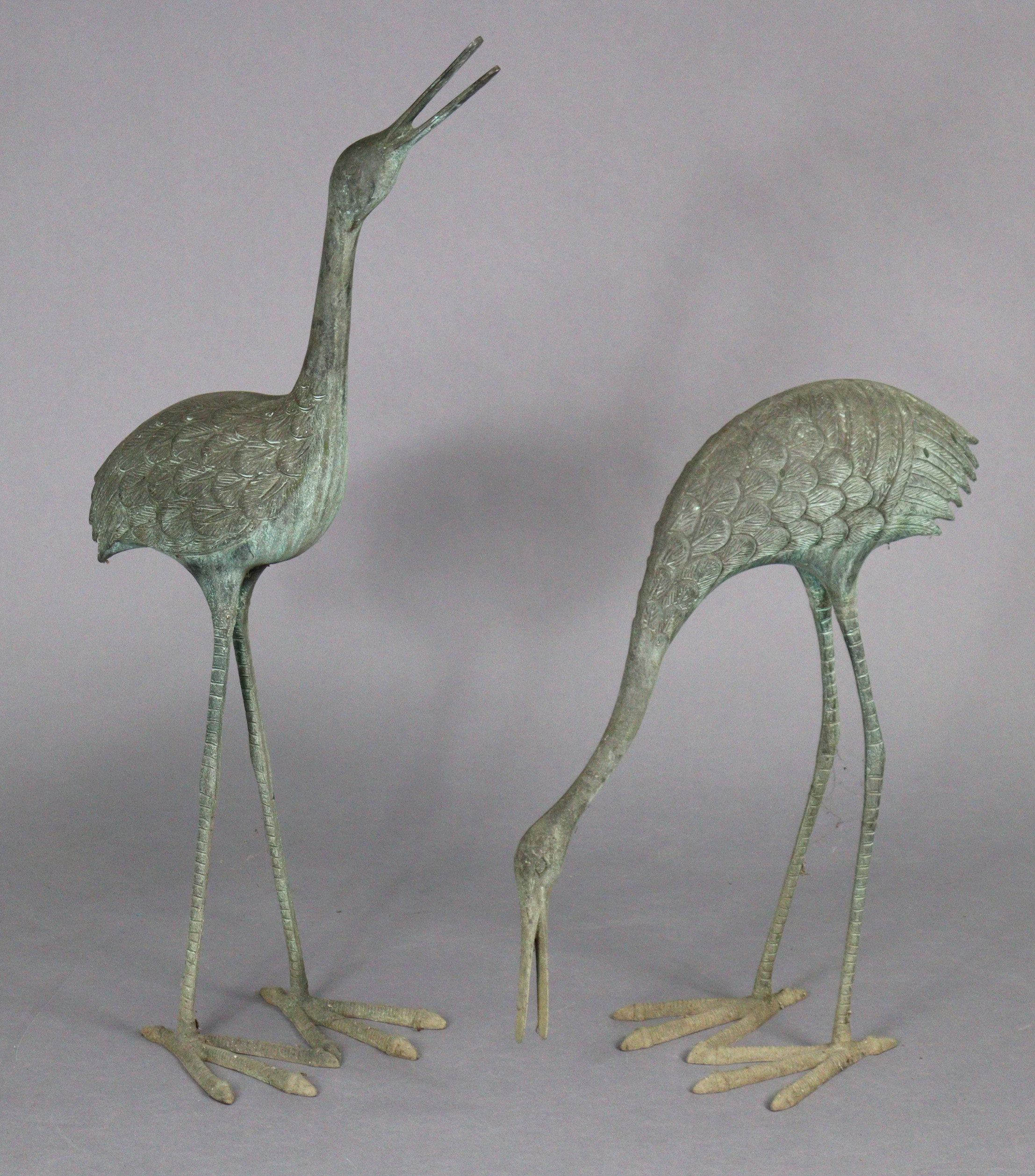 A pair of 20th century metal garden ornaments in the form of standing crane, 35” & 23” high.