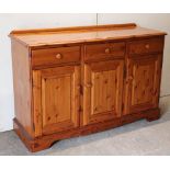A pine sideboard fitted three frieze drawers above cupboard enclosed by three fielded panel doors, &