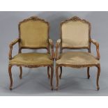 A pair of reproduction carved beech frame fauteuils each with a padded seat & back upholstered