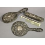 A silver embossed-backed three-piece part dressing table set, hallmarks rubbed; & a similar comb.