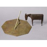 A Brutalist metal ornament in the form of a standing cow, signed PP 1/6, 4” high; & a brass sundial,