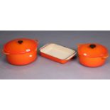 A Le Creuset ‘Flame’ orange enamelled 11” circular two-handled casserole dish & cover; a 9½”
