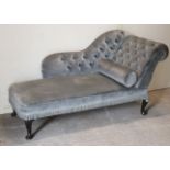 A reproduction chaise-longue with a buttoned shaped back, scroll-arm, & sprung seat upholstered pale