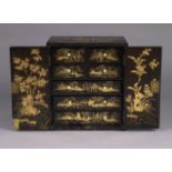 An early 19th century Chinese export lacquer table cabinet, with all-over gilt Chinoiserie