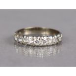 A diamond half-hoop ring set nine graduated round-cut stones to a white metal shank marked “18ct”;