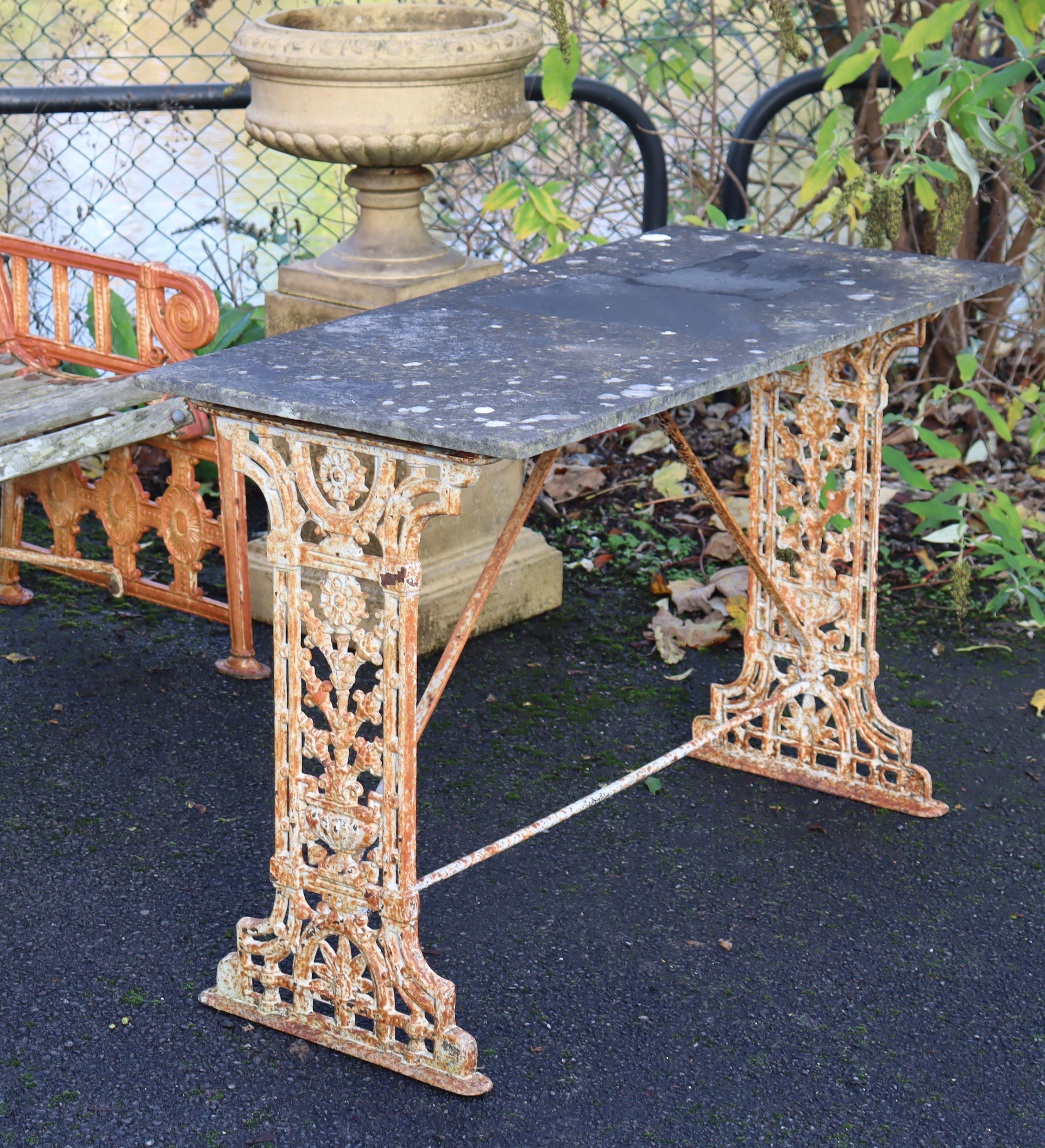 A 19th century cast iron garden table, the pierced ends of foliate design with rectangular stone