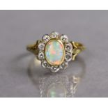 An opal & diamond ring, the oval-cut opal set within a border of ten small diamonds to an 18ct.