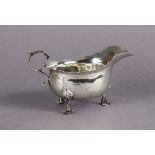 An Edwardian silver oval sauce boat with cut-card rim, leaf-scroll handle, & on three pad feet, 5.5“