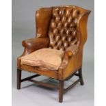 An 18th century style mahogany wing-back armchair upholstered buttoned & brass-studded tan leather,