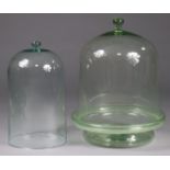 A large pale green glass food dish & domed cover with globular handle, the base with raised edge,