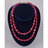 A necklace of opaque ruby oval facetted beads, 19¾” long; & a similar necklace, 16½” long.